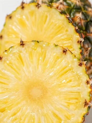Ananas i freskët, i prerë në feta mbi tavolinë druri rustike
