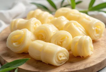 Filiza bambuje të prerë në feta në dërrasë prerëse, të rrethuar me perime të freskëta