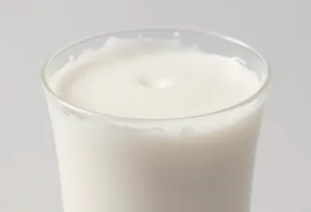 Një gotë dhe një shishe qumësht i freskët mbi banak kuzhine të çelët, pa elemente shtazore