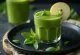 Smoothie jeshil në gotë të lartë, i zbukuruar me perime dhe fruta të freskëta