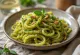 Makarona vegane me salcë pesto, të shërbyera të freskëta me borzilok dhe stika pishe të pjekura.