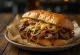 Sendviç Philly Cheesesteak i servirur me patate të skuqura dhe sallatë